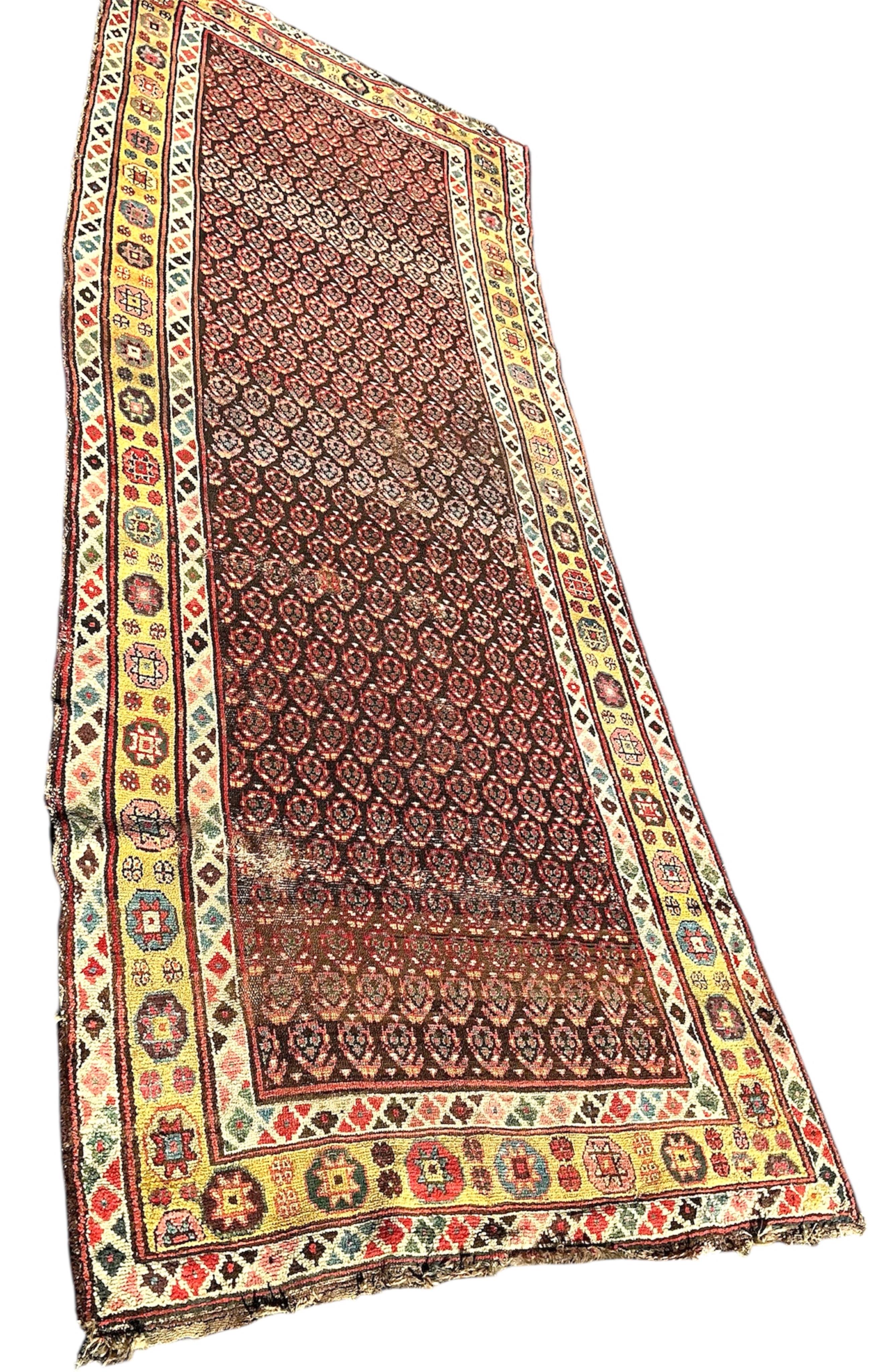 An antique Senneh red ground hall carpet, 325 x 128cm